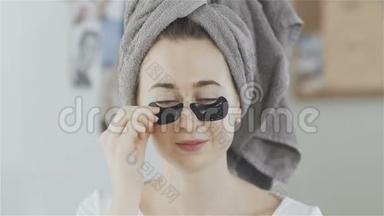 头上戴毛巾的女人摘下一片胶原蛋白水解面膜。